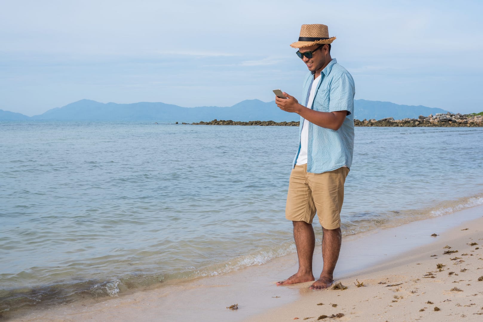 Young,Asian,Man,Using,Smartphone,On,The,Beach Hotel technology push notifications 3