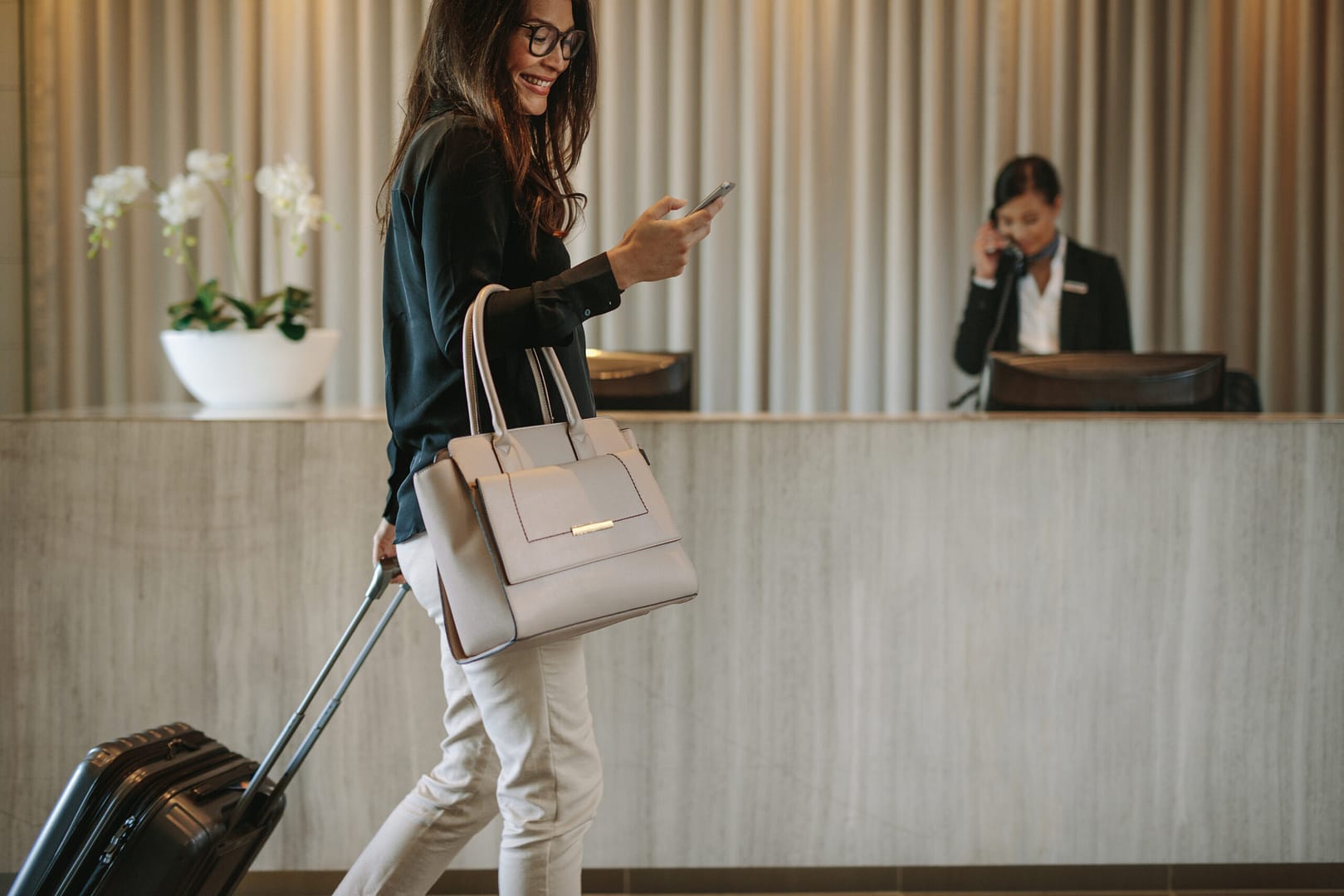 Woman,Using,Mobile,Phone,And,Pulling,Her,Suitcase,In,A Contactless check-in