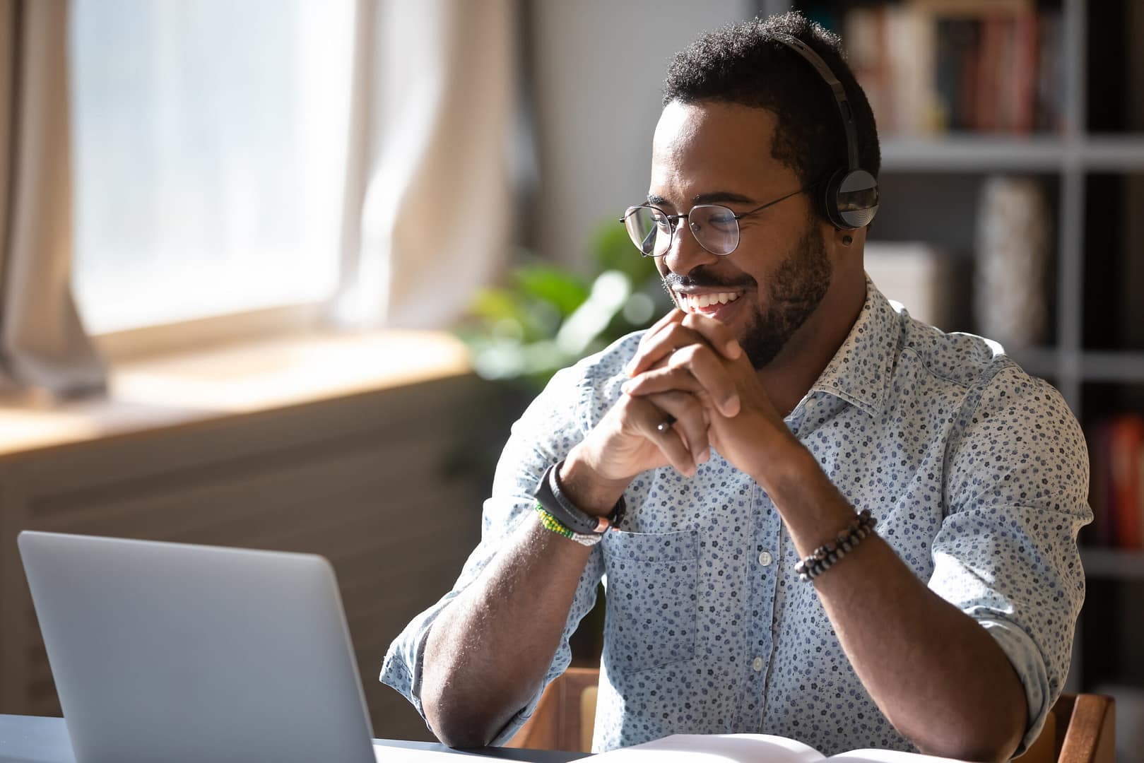 Happy,Millennial,African,American,Man,In,Glasses,Wearing,Headphones,,Enjoying PBX phone systems for hotels 2